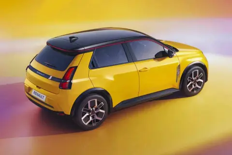 Nowe Renault 5 w jaskrawym żółtym kolorze z czarnym dachem i czerwonymi akcentami, prezentuje się dynamicznie na tle gradientowego tła.