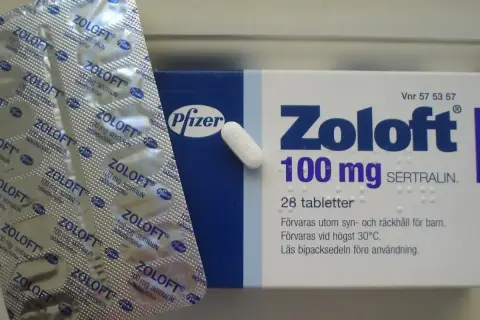 Opakowanie leku Zoloft 100 mg z sertraliną i blister z tabletkami.