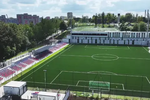 Nowy stadion Polonii Bytom z zieloną murawą, trybunami w kolorach czerwonym i niebieskim oraz nowoczesnym budynkiem klubowym.