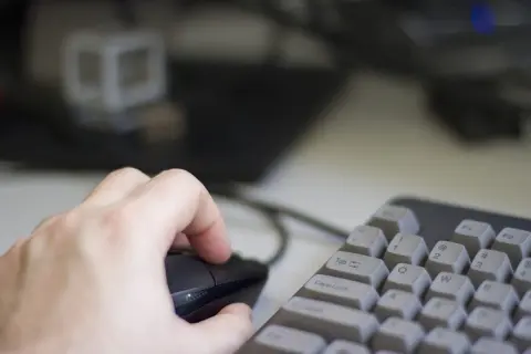Dłoń trzyma myszkę, klawiatura w pobliżu. Używanie trybu incognito do prywatnego przeglądania.