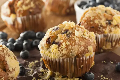 Frisch gebackene Blaubeermuffins mit Streuseln, ein köstliches Muffins Rezept, umgeben von frischen Blaubeeren.