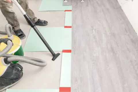 Préparation du sol avant la pose du parquet : nettoyage avec aspirateur. Le temps de séchage du ragréage est crucial.