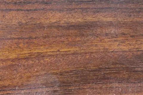 Textura rica de madera mongoy, con vetas oscuras y tonos dorados que evocan la naturaleza.