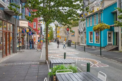 Kolorowa ulica w Reykjaviku, z flagami Islandii i szyldem "korona islandzka kantor".