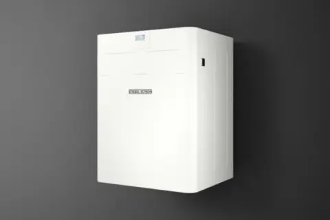 Biały, nowoczesny stiebel eltron rekuperator zamontowany na ciemnej ścianie. Urządzenie z dyskretnym wyświetlaczem i logo producenta.