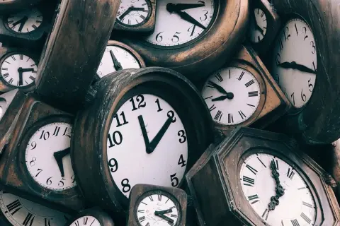 Zbliżenie na wiele starych zegarów ściennych z różnymi tarczami i wskazówkami.