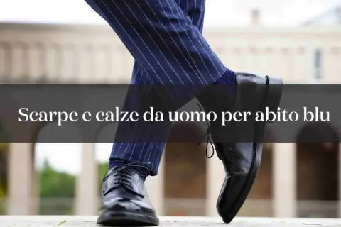Primo piano di un uomo con abito blu gessato e calze blu a pois, abbinate a scarpe eleganti nere.