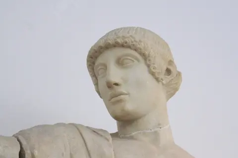 Buste en marbre d'Apollon, dieu grec ou romain, aux boucles caractéristiques et au regard pensif.