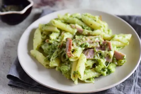 Penne z brokułami i kawałkami szynki w kremowym sosie śmietanowym, posypane serem. Pyszne danie, które zachwyci każdego.