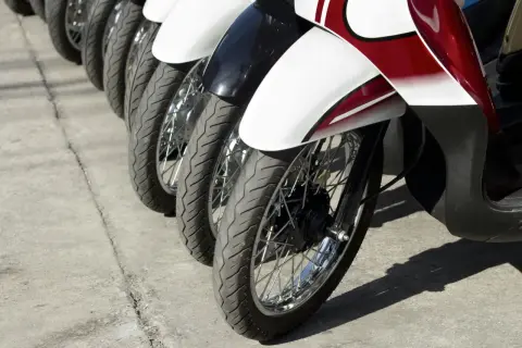 Rzędy motocykli gotowe do dpd transportu. Widoczne koła, opony i błotniki w kolorze białym, czarnym i czerwonym.