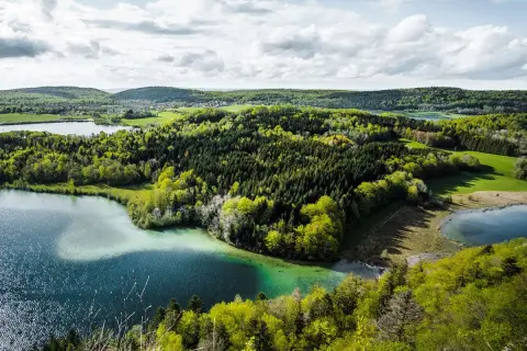 Paysage jurassien avec lacs et forêts verdoyantes, idéal pour une randonnée Jura 5 jours.