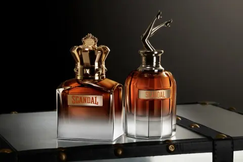 Dwa flakony perfum Jean Paul Gaultier Scandal Meski: jeden z koroną, drugi z nogami w szpilkach.