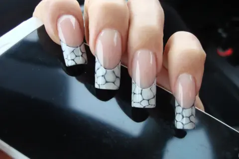 Manucure française avec un motif écaille de tortue sur les ongles, posée sur un écran noir.
