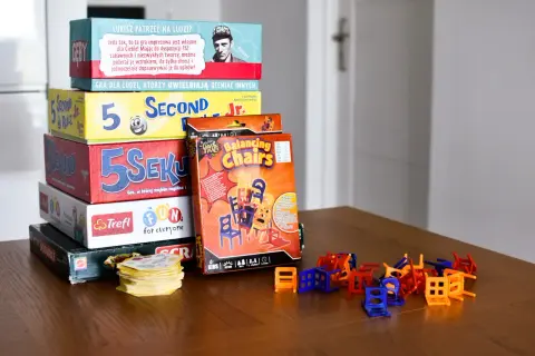 Stos pudełek z popularnymi grami dla dzieci: "5 Sekund", "Balancing Chairs", "Scrabble" i inne. Idealne na rodzinne wieczory.
