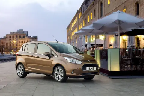 Brązowy Ford B-Max na tle miejskiej zabudowy. Idealny do miasta, jego wymiary sprawiają, że parkowanie to przyjemność.