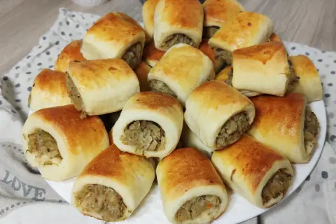 Złociste paszteciki z pieczarkami i kapustą, ułożone na talerzu, kuszą swoim wyglądem i aromatem.