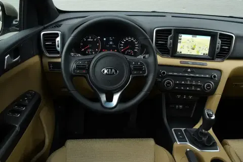 Wnętrze Kia Sportage IV z beżową tapicerką, multimediami z nawigacją i wielofunkcyjną kierownicą.