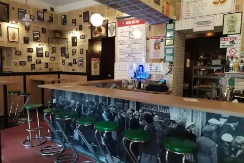 Stylowy bar z zielonymi stołkami i czarno-białą fototapetą. Idealne miejsce, gdzie na drinka w Krakowie.