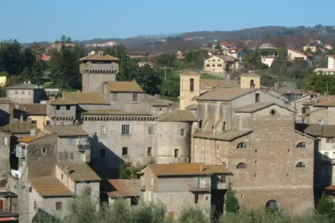 Borgo medievale di Carbognano, Viterbo, con torri e case in pietra sotto un cielo azzurro.