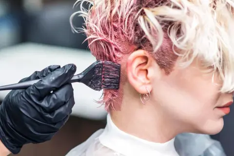 Aplicando tinte rosa en el cabello. Si te manchas la piel, aprende como quitar manchas de tinte de la piel fácilmente.