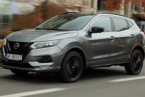 Szary Nissan Qashqai 2019 z czarnymi felgami pędzi ulicą, otoczony jesienną scenerią.