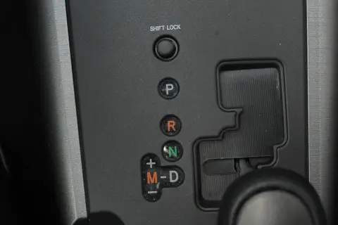 Panel z przyciskami skrzyni biegów: P, R, N, M-D. Obok przycisku "SHIFT LOCK" znajduje się otwór do jego zwolnienia.