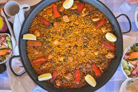 Paella gigante con pollo, judías verdes, pimientos rojos y limón. Los ingredientes paella lucen deliciosos en este plato tradicional español.