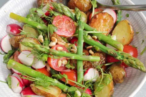 En härlig rostad potatissallad med sparris, rädisor och tomater, toppad med pinjenötter och dill.