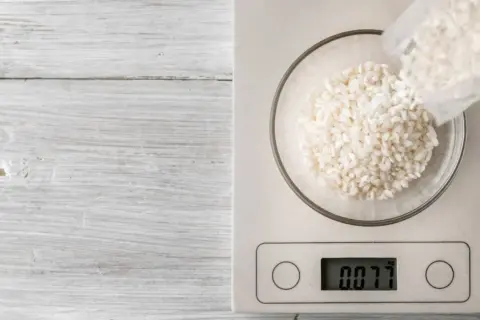 Balanza digital muestra 0.077 kg de arroz en un bol. Ideal para calcular cuánto arroz por persona.