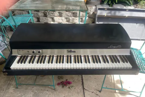 A vintage Fender Rhodes Stage Piano Mark I, a classic among labs vintage keys, sits on a teal metal stand outdoors.
