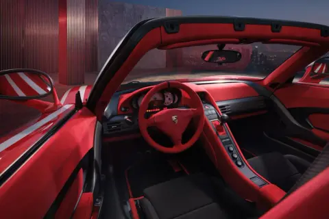 Wnętrze czerwonego Porsche Carrera GT z widokiem na nocne miasto.