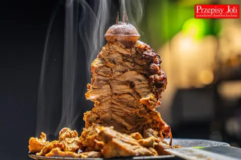 Gorący, parujący kebab z mięsa mielonego, obracający się na rożnie, z chrupiącymi kawałkami mięsa na talerzu.