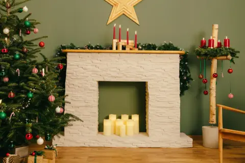 Festliche Szene mit geschmücktem Weihnachtsbaum, selbstgebauter Kaminkonsole, Kerzen und Geschenken.