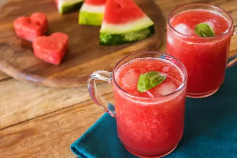 Refrescante bebida de sandía con un toque de limón, servida con hielo y hojas de albahaca.