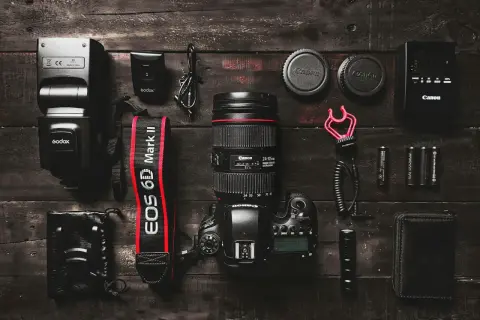 Zestaw sprzętu fotograficznego: aparat Canon EOS 6D Mark II, obiektyw, lampa błyskowa, baterie i akcesoria. Aparat fotograficzny służy do utrwalania chwil.
