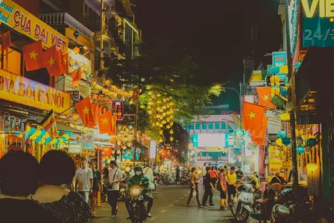 Tętniąca życiem nocą ulica w Ho Chi Minh (miasto), ozdobiona flagami Wietnamu i lampionami.