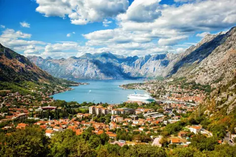 Bucht von Kotor, Montenegro: rote Dächer, Berge, Kreuzfahrtschiff. Entdecken Sie Montenegro Geheimtipps in dieser malerischen Kulisse.