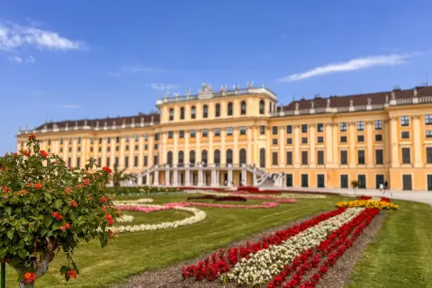 Wiedeń atrakcje: Pałac Schönbrunn z barwnymi rabatami kwiatowymi i zielonymi trawnikami.