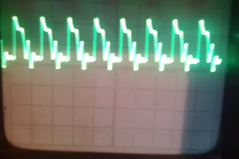 Zielone, kwadratowe fale na ekranie oscyloskopu, przypominające schodki.