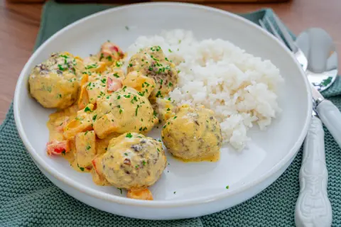 Fleischbällchen in cremiger Sauce mit Paprika und Reis. Ein Gericht, das zeigt, dass reis noch hart sein kann, wenn er nicht richtig gekocht wird.
