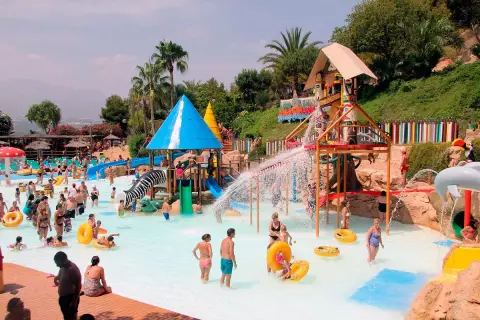 En livlig dag på Aqualandia Benidorm med folk som njuter av vattenrutschkanor och pooler under en solig himmel.