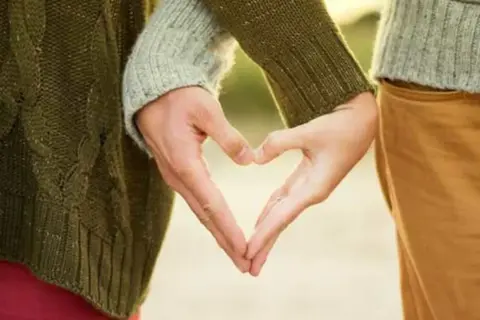 Zwei Hände formen ein Herz, ein Symbol für eine tiefe Partnerbeziehung.
