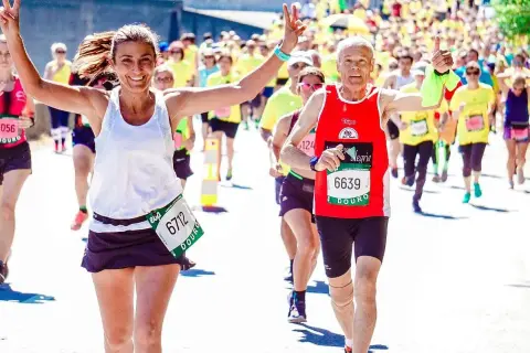 Uśmiechnięci biegacze na maratonie, radość i determinacja. Jak przygotować się do maratonu? Warto czerpać inspirację z ich pozytywnej energii!