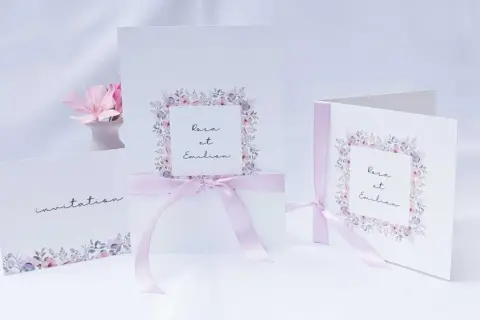 Trois faire-part de mariage délicats, ornés de fleurs pastel et de rubans roses. L'un d'eux mentionne "Rosa et Emilien".