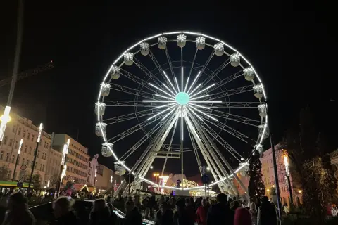 Nocny plac wolności poznań rozświetla ogromne koło widokowe. Tłumy ludzi spacerują wśród świątecznych iluminacji.