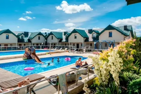 Rodzinny wypoczynek w domkach apartamentowych Fulay Premium. Dzieci bawią się w basenie ze zjeżdżalnią, dorośli relaksują się na leżakach.
