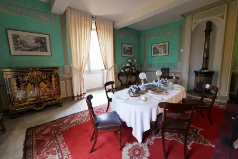 Salle à manger du **château de Saché**, avec une table dressée, un buffet orné et des murs aux motifs décoratifs.