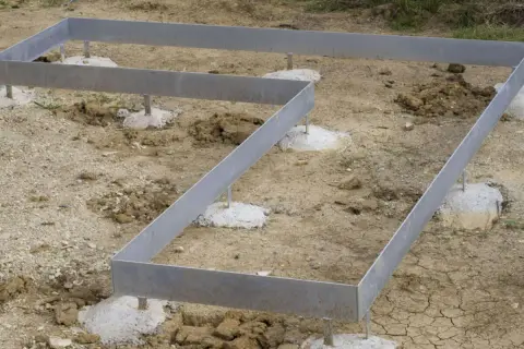 Metallrahmen auf Betonfundamenten für ein neues Haus. Das punkt fundament ist vorbereitet.