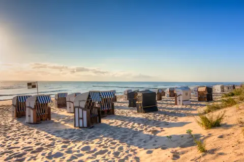 Reihe von Strandkörben am Strand Deutschland, mit Blick auf das Meer und den blauen Himmel.