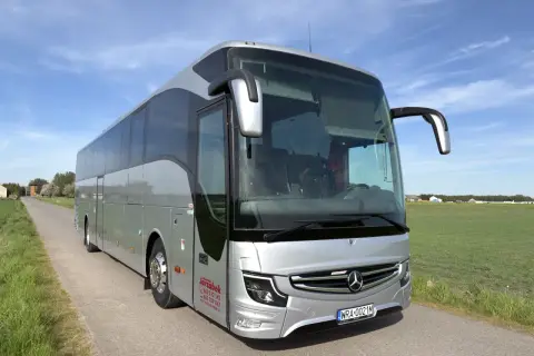 Srebrny autokar na tle błękitnego nieba. Zastanawiasz się, ile miejsc ma autokar? Ten wygląda na przestronny, idealny na wycieczki.